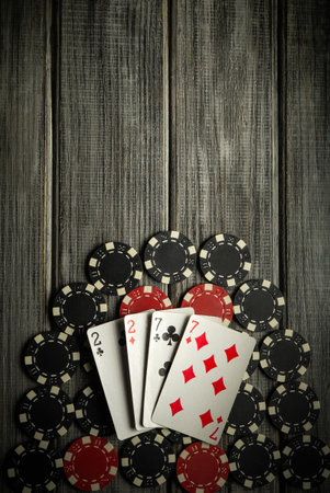 A set of playing cards featuring pairs and a seven rests atop a stack of black and red poker chips...