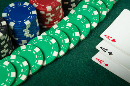 An exciting game of poker, brightly colored chips are laid out around a winning hand of aces on a...