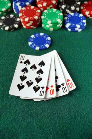 A set of playing cards shows four tens, a winning hand at poker. Surrounding the cards are various...