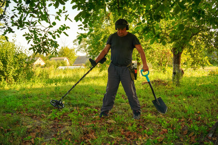 A dedicated treasure hunter is using a metal detector and a shovel in a vibrant, sunlit field...