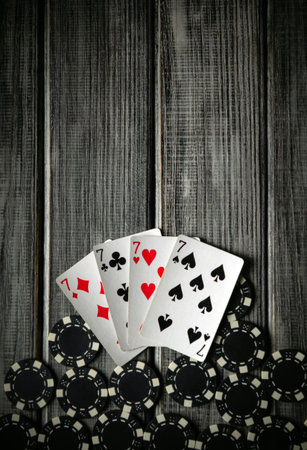 Four playing cards show winning hands with red hearts and black spades on a rustic wooden table,...