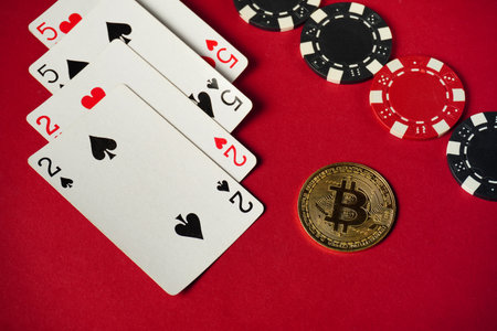 Four playing cards showing two of hearts and two of spades are arranged beside multiple poker chips...