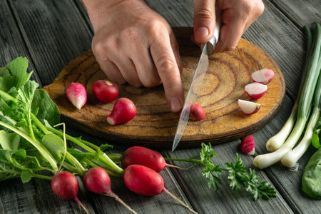 Hands skillfully chop radishes and prepare green onions on a cutting board surrounded by fresh...