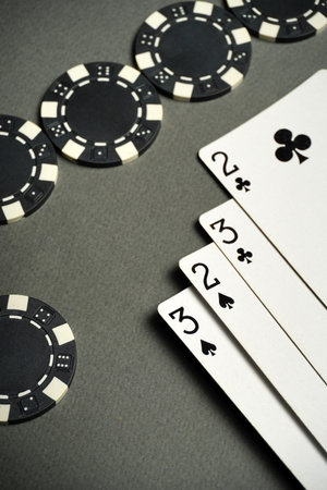 Perhaps enjoying the evening's game, players gather around a gray table with poker cards and chips,...