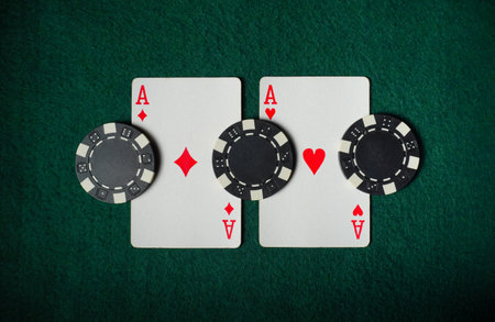 Two aces, one in hearts and one in diamonds, are placed alongside poker chips on a green felt...