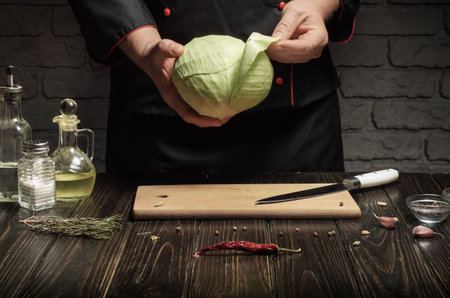 Chef peeling cabbage with hands. Preparing vegetable dish for breakfast with spices in restaurant.の写真素材