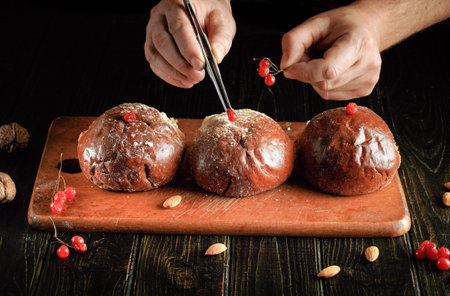 Carefully adding viburnum berries to buns with tweezers in the hands of an experienced chef. Serving...