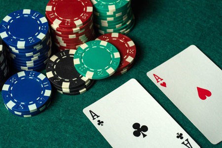 Two playing cards show aces while colorful poker chips are stacked nearby. Friends gather around a...
