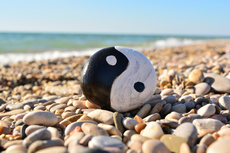 yin yang symbol painted on a rock on the sea beachの写真素材
