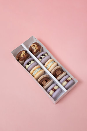 Colorful macaroons in a white box on a pink background