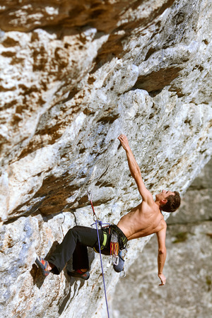 Young man climbs on a rocky wallの写真素材