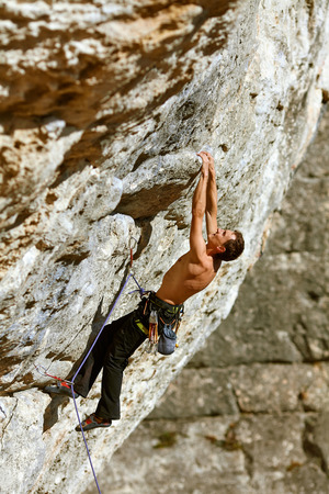 Young man climbs on a rocky wallの写真素材