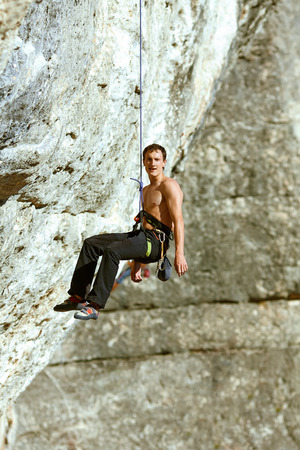 Young man climbs on a rocky wallの写真素材