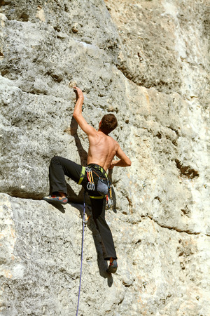 Young man climbs on a rocky wallの写真素材