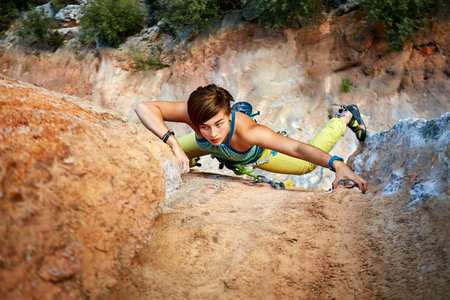 female rock climber climbs on a rocky wallの写真素材