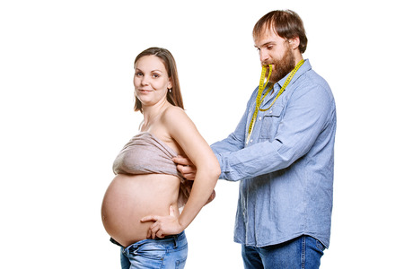 stout man with measure tape and pregnant woman on a white background, isolated on a white backgroundの写真素材