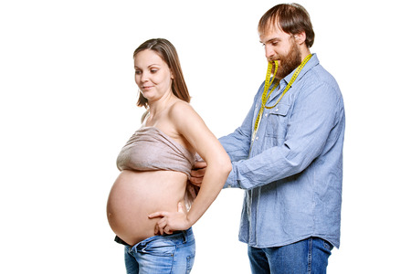 stout man with measure tape and pregnant woman on a white background, isolated on a white backgroundの写真素材