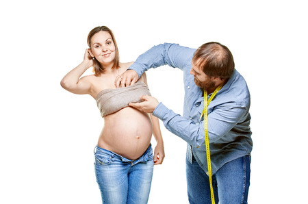 stout man with measure tape and pregnant woman on a white background, isolated on a white backgroundの写真素材