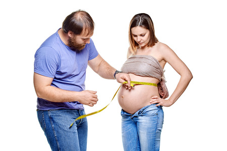 stout man with measure tape and pregnant woman on a white background, isolated on a white backgroundの写真素材