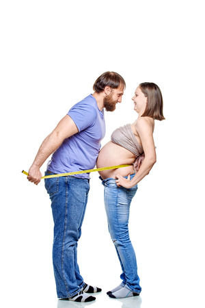 stout man with measure tape and pregnant woman on a white background, isolated on a white backgroundの写真素材