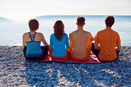 group of friends on the beach at the sunrise. view from the backの写真素材