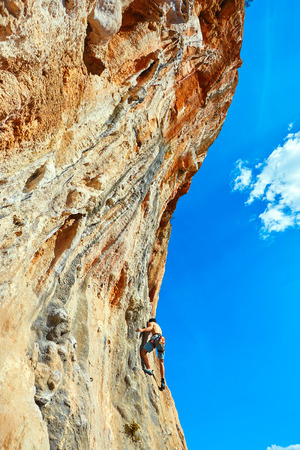 male rock climber climbs on a rocky wallの写真素材