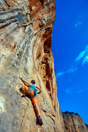 female rock climber climbs on a rocky wallの写真素材