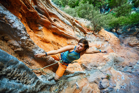 female rock climber climbs on a rocky wallの写真素材