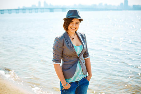 young woman on the sea beach at the morning. woman dressed in sneakers jeans jacket and hatの写真素材