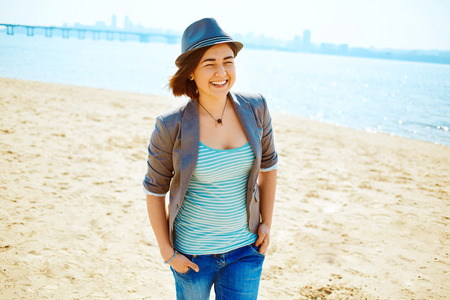 young woman on the sea beach at the morning. woman dressed in sneakers jeans jacket and hatの写真素材