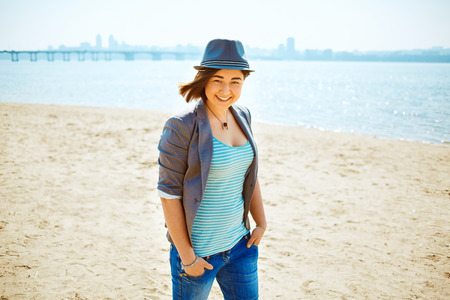 young woman on the sea beach at the morning. woman dressed in sneakers jeans jacket and hatの写真素材