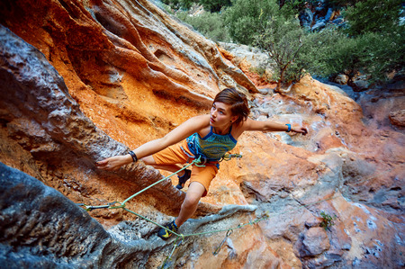 female rock climber climbs on a rocky wallの写真素材