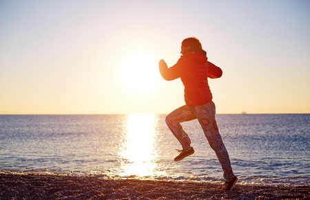 happy girl running on the beach at sunrise against the sun. silhouetteの写真素材