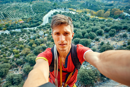 young attractive man make selfie from the cliff on the gardens backgroundの写真素材
