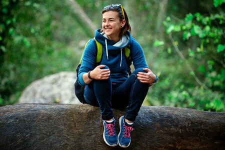Active healthy woman hiking in beautiful forest. Portrait of happy smiling young woman resting of...