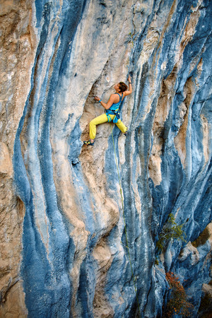 female rock climber climbs on a rocky wallの写真素材