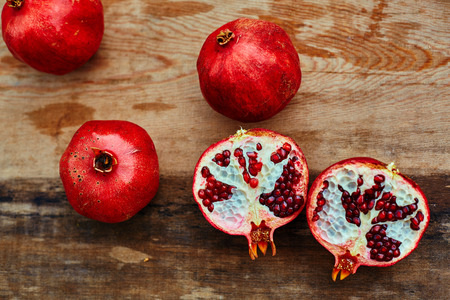 ripe cracked raw pomegranates on a dark wooden backgroundの写真素材