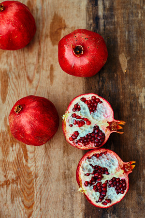 ripe cracked raw pomegranates on a dark wooden backgroundの写真素材