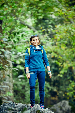 Active healthy woman hiking in beautiful forest. Portrait of happy smiling young woman resting of forest clearing during hike holidays.の写真素材