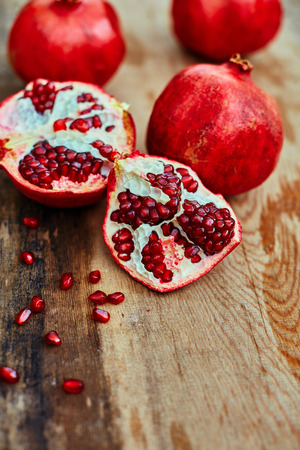 ripe cracked raw pomegranates on a dark wooden backgroundの写真素材