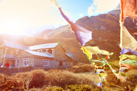 Hotel in mountains and traditional flags with prayer on the foreground.   Trek around Annapurna mount. Tilicho lake region. Nepalの写真素材