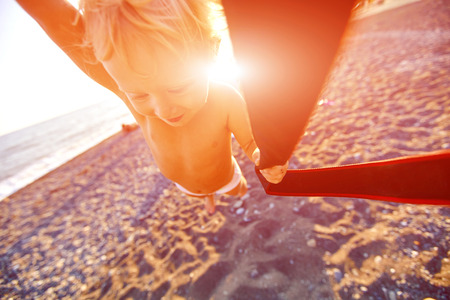 someone turns a little girl on the beach at sunsetの写真素材