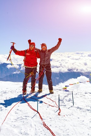 hikers at the top of a pass with backpacks meeting the sunrise in the mountainsの写真素材