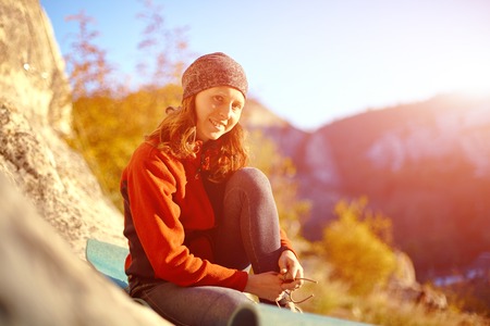 athletic woman puts shoes sitting on a rugの写真素材