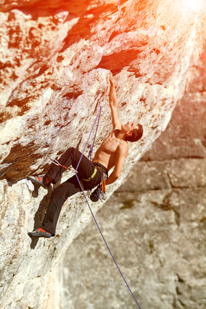 Young man climbs on a rocky wallの写真素材