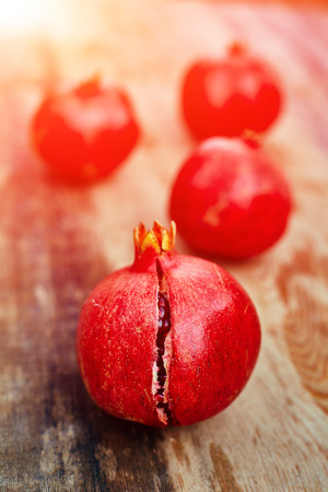 ripe cracked raw pomegranates on a dark wooden backgroundの写真素材