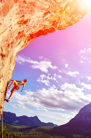 female rock climber climbs on a rocky wallの写真素材