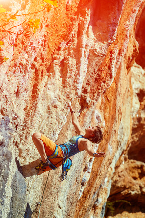 female rock climber climbs on a rocky wallの写真素材