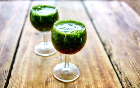 Green raw coctail. Green vegetable juice in wine glass on wooden background. Selective focusの写真素材
