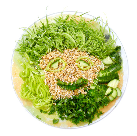 funny smiley face from vegetables. salad of fresh cabbage, pepper, cucumber,  parsley and sprouted lentils on  plate on white background.の写真素材